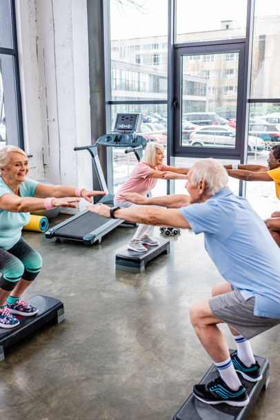 joyeux sportif senior multiethnique synchrone faire squats sur les plates-formes étape à la salle de gym
 - Photo, image