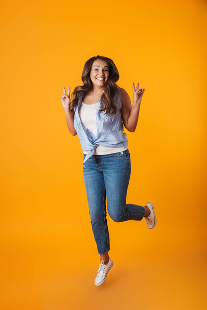 Full length portrait of an excited young casual woman isolated over yellow background, celebrating success - Φωτογραφία, εικόνα