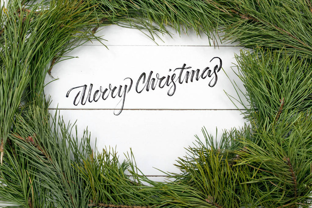 A karácsonyi üdvözlő kártya fenyő ága és dekoráció a deszkát, boldog karácsonyt felirat. Karácsonyi fenyő fa háttér előtt levelet. Másolja a hely - Fotó, kép