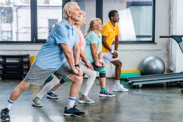 vue de côté des athlètes multiethniques seniors étirement synchrone à la salle de gym
 - Photo, image