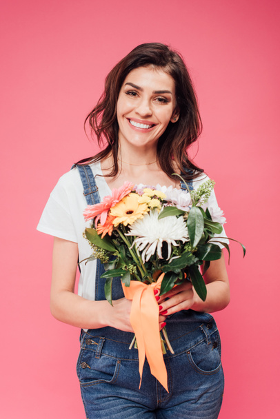 happy woman holding flower bouquet and looking at camera isolated on pink - Фото, зображення