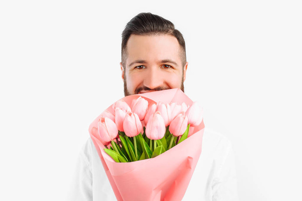 Elegant man with a beard holding a bouquet of tulips, a gift for Valentine's Day. On a white background - Foto, imagen