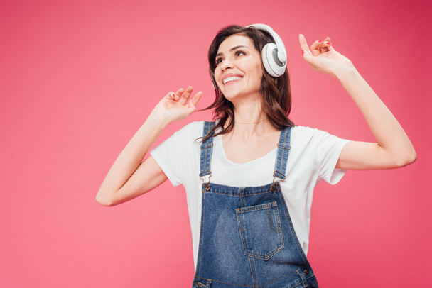 happy woman listening music in headphones isolated on pink - Фото, зображення