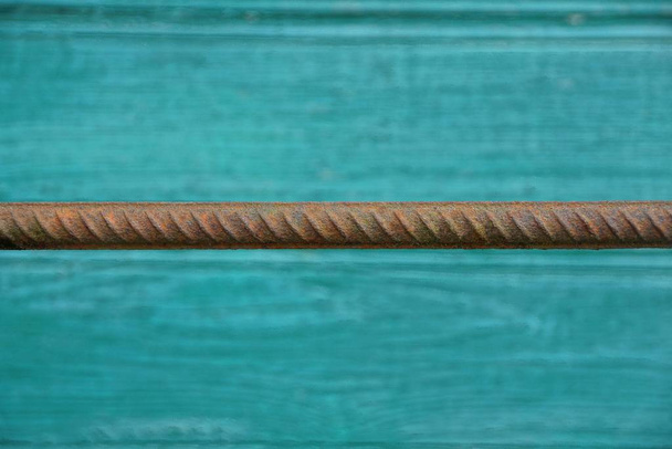eine lange rostige Stahlstange gegen eine grüne Wand - Foto, Bild