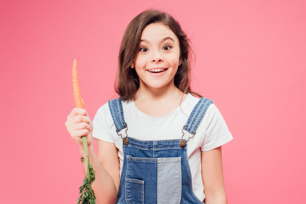 happy kid holding carrot isolated on pink  - Fotografie, Obrázek