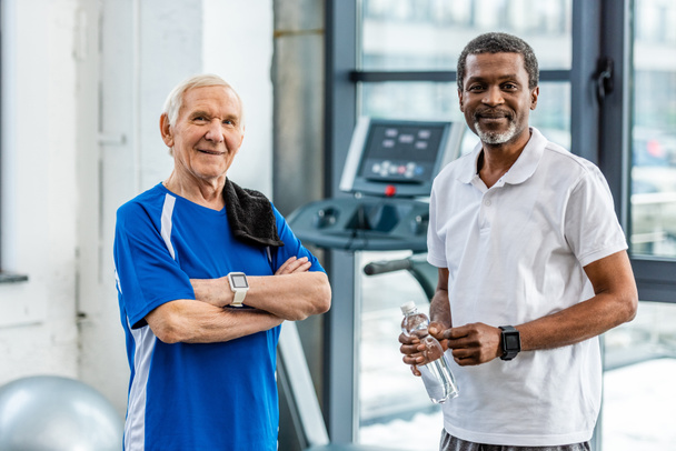 heureux multiculturels sportifs matures avec smartwatches debout à la salle de gym
 - Photo, image