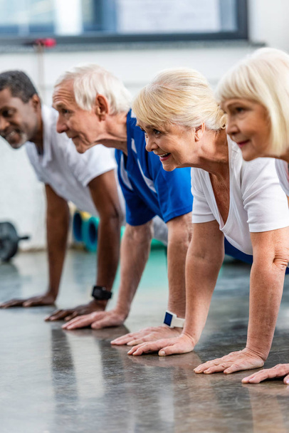 Lächelnde verstümmelte Senioren beim Planken in Sporthalle  - Foto, Bild