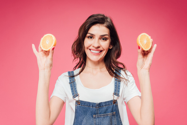 attractive woman holding oranges in hands isolated on pink  - Foto, imagen