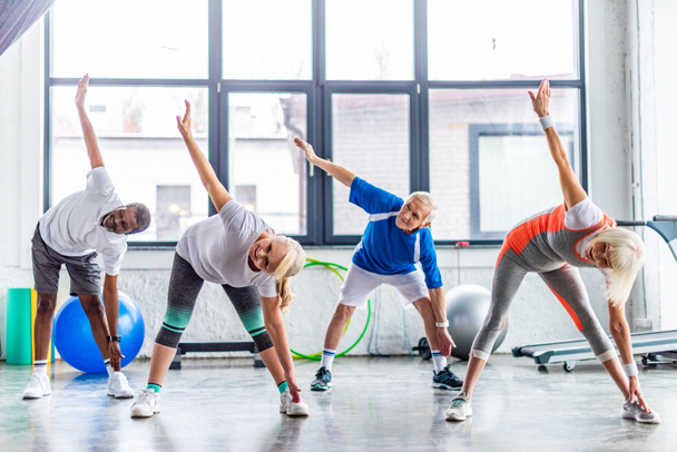 multiethnic senior sportspeople synchronous exercising at sports hall - Valokuva, kuva