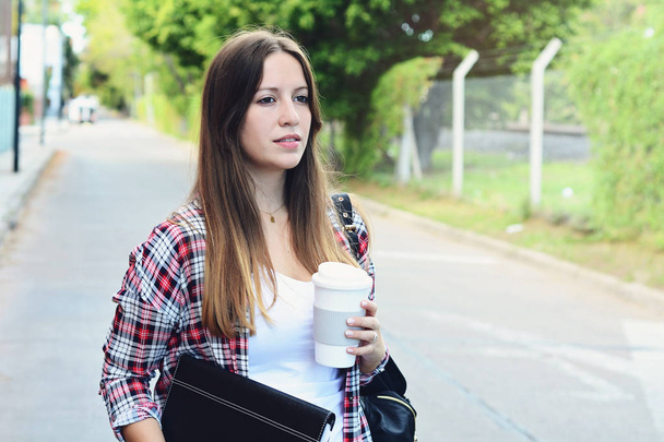 Portrait of beautiful woman holding paper coffee cup in the street. Urban city scene. Outdoors - Foto, Imagen