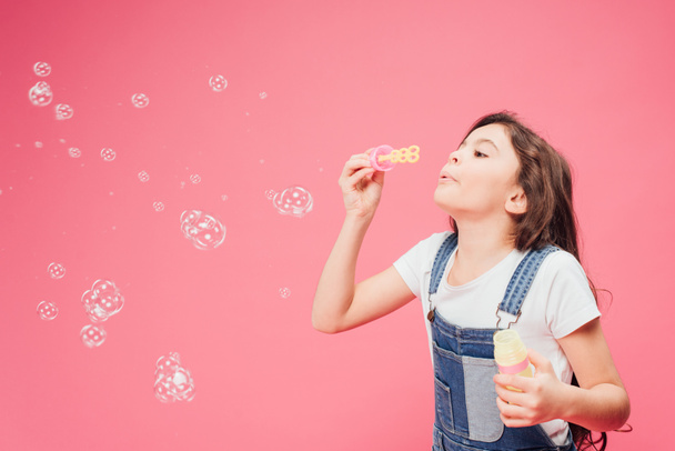 joyful kid blowing soap bubbles isolated isolated on pink - Foto, afbeelding