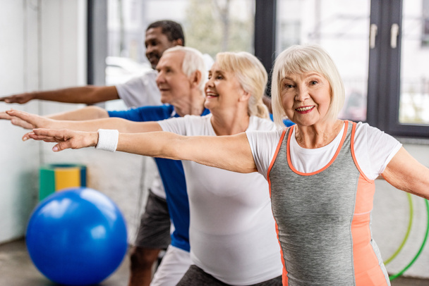 счастливые старшие мультиэтнические спортсмены синхронно тренирующиеся в спортзале
 - Фото, изображение
