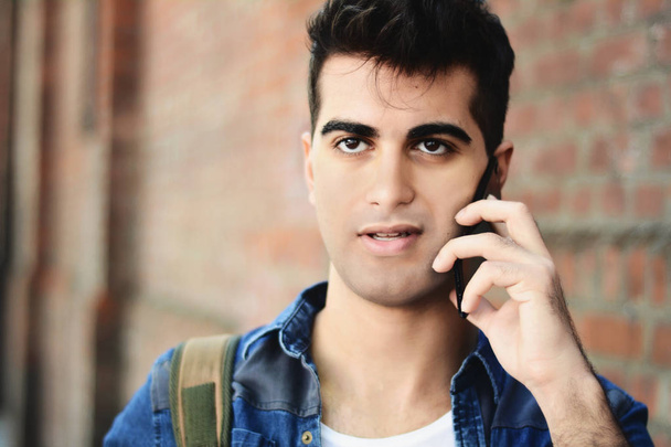 Portrait of young latin man talking on the phone in the street. Outdoors. - Fotó, kép