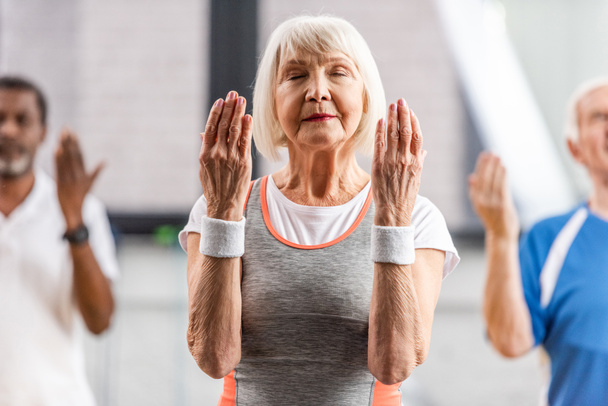 selektywne focus starszy sportsmenki z zamkniętych oczu podejmowania ćwiczeń w siłowni - Zdjęcie, obraz