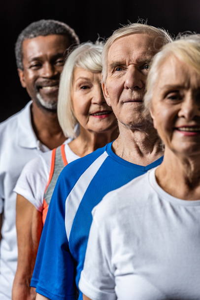 happy multicultural senior sportspeople standing isolated on black - Photo, Image