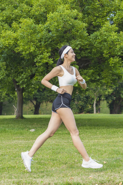 Young Asian woman smiling jogging in the park - Fotó, kép