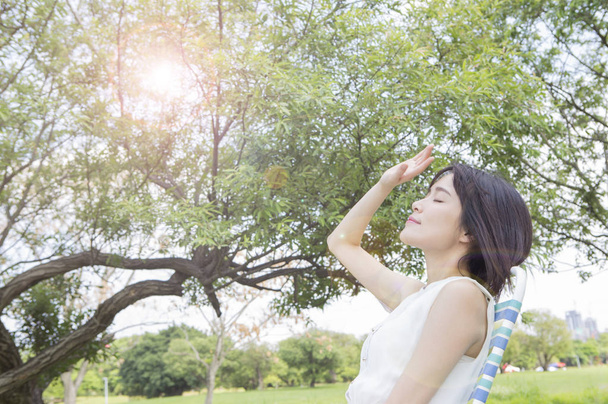 Giovane donna asiatica indossa un abito bianco seduto sulla panchina con un sole abbronzatura
 - Foto, immagini