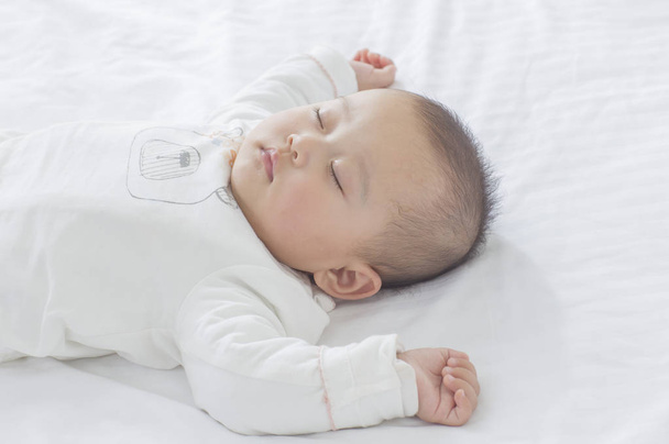 Jovem bebê asiático dormindo na cama
 - Foto, Imagem