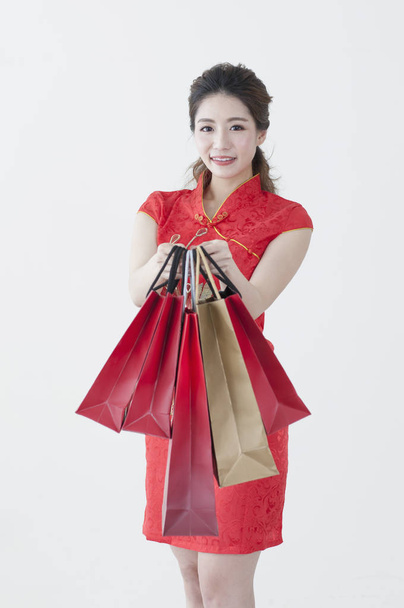 Mladá Čínská žena nosí cheongsam, že některé dárky a usmívá se na kameru - Fotografie, Obrázek