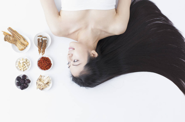 A beautiful Asian woman lying next to some Chinese medicines - 写真・画像