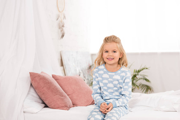 adorable smiling child sitting on bed in morning - Foto, imagen