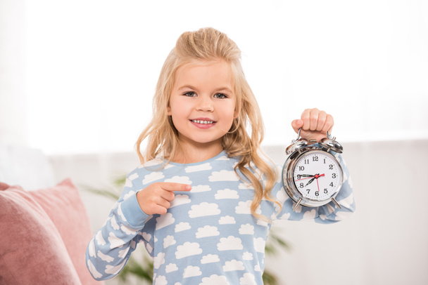 smiling cute child pointing with finger at clock  - Fotoğraf, Görsel