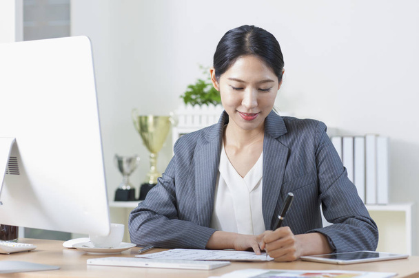Young Asian woman sitting at the desk and writing - Foto, Bild