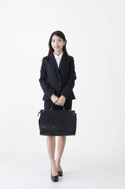 Young Asian woman wearing a suit holding a brief case and smiling at the camera, - Foto, Imagen