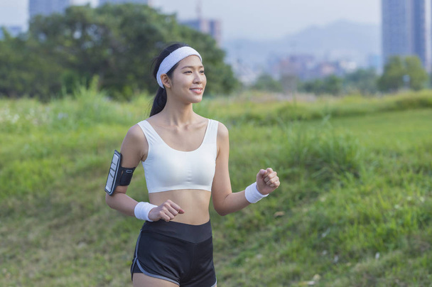 Young Asian woman smiling jogging in the park - Foto, afbeelding
