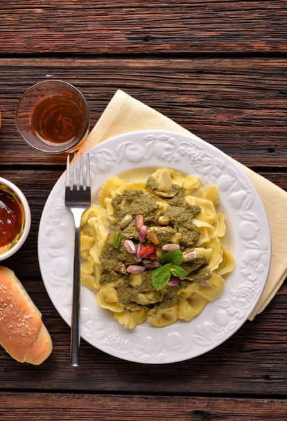 Cappelletti pasta z pistacji krem i papryki na biały talerz na stole - Zdjęcie, obraz