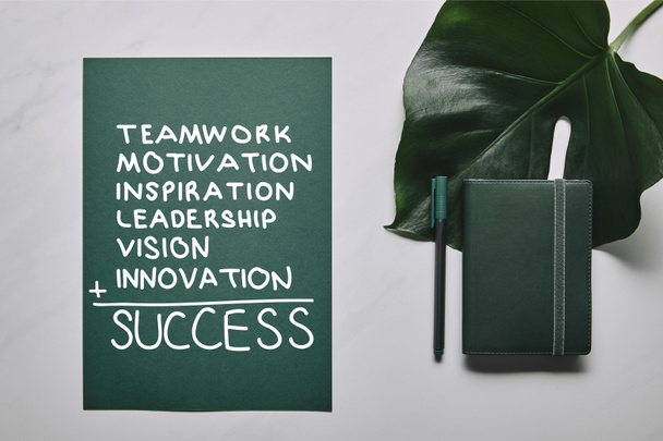 Green stationery set and monstera leaf on white marble background with "success" inspiration - Photo, Image