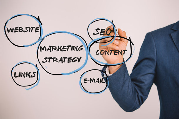 visión parcial del empresario escribiendo estrategia de marketing con marcador aislado en gris
 - Foto, imagen