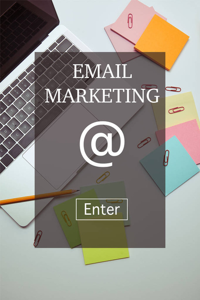 "e-posta pazarlama" yazı ile beyaz masa üzerinde laptop, Kağıt etiketleri, kalem ve kağıt klipleri yükseltilmiş görünümü  - Fotoğraf, Görsel