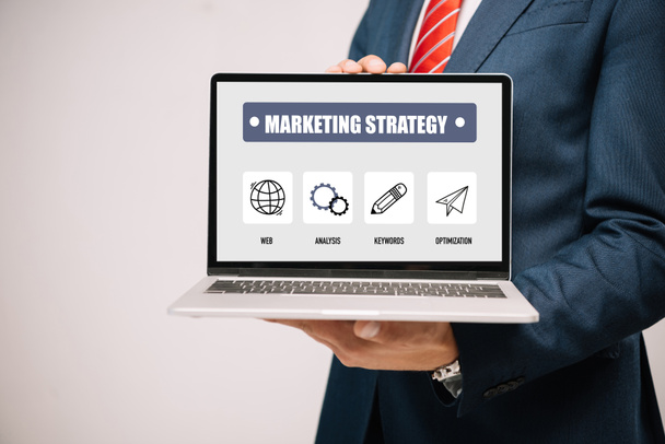 обрізаний вид бізнесмена в костюмі представлення ноутбука з маркетинговою стратегією ізольовано на сірому
 - Фото, зображення