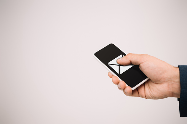 vista recortada del hombre de negocios utilizando el teléfono inteligente con el icono de correo electrónico aislado en gris
 - Foto, Imagen