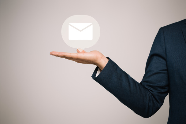 vista parcial del hombre de negocios en traje de gestos y la presentación de icono de correo electrónico aislado en gris
 - Foto, imagen