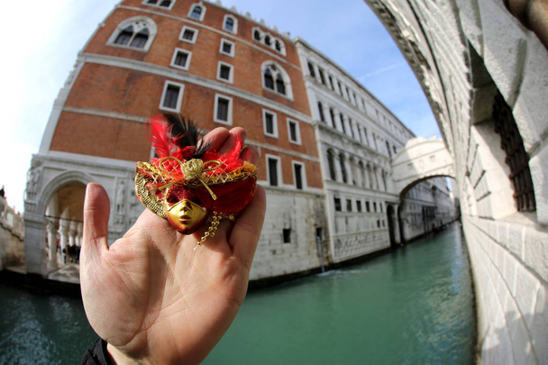 main avec le petit masque et en arrière-plan le célèbre Pont des Soupirs à Venise en Italie
 - Photo, image