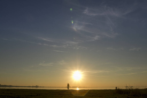 tramonto sul lago uomo in piedi lontano
 - Foto, immagini