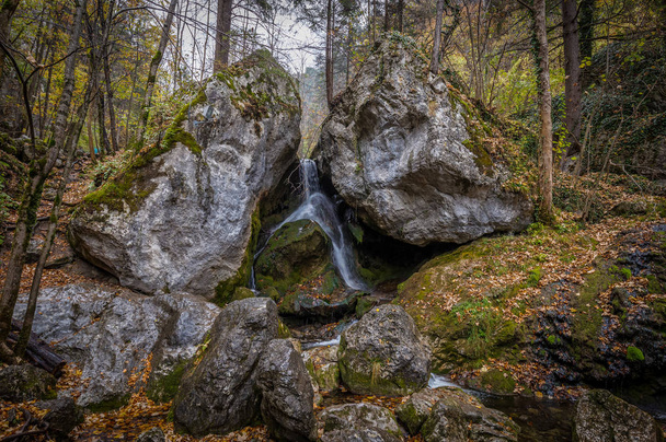 Wasser fällt zwischen zwei großen Felsen im Herbstwald bei Myraflle, Österreich - Foto, Bild