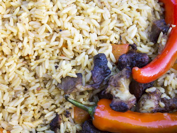Pilaf. In the foreground are pieces of meat and red hot peppers. - Photo, Image