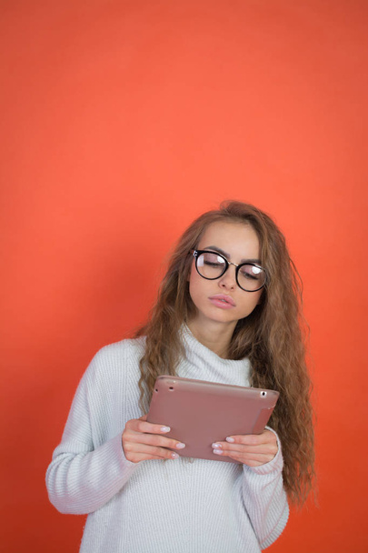 Pretty young woman holding and uses tablet - Foto, afbeelding
