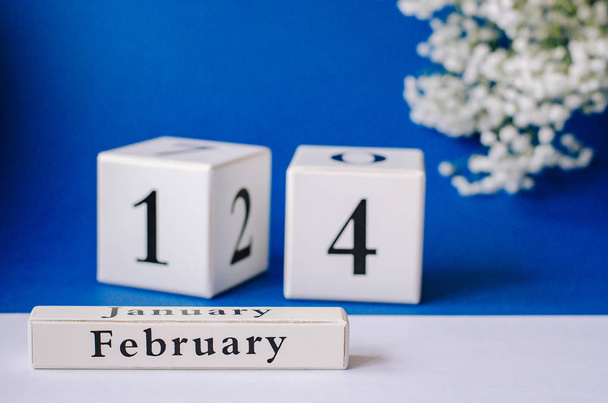 Calendario con la fecha del día de todos los amantes es el 14 de febrero. fondo azul con blanco con una ramita de gypsophila blanca
. - Foto, imagen