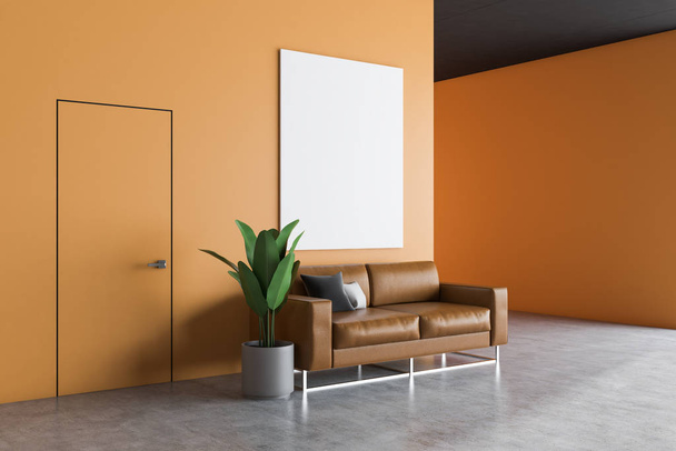 Office waiting room interior with orange walls, concrete floor, leather sofa with cushions and vertical poster hanging above it. 3d rendering mock up - Foto, imagen