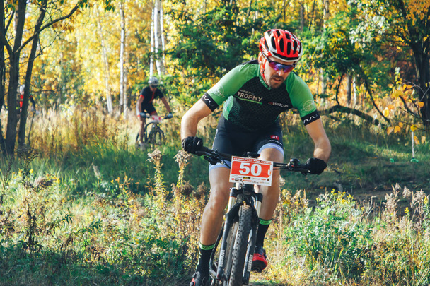 14. Oktober 2018 - Minsk, Weißrussland: Olympischer Langlauf-Cup 2018 xco in medvezhino, Männer mit Fahrrädern auf Waldweg - Foto, Bild