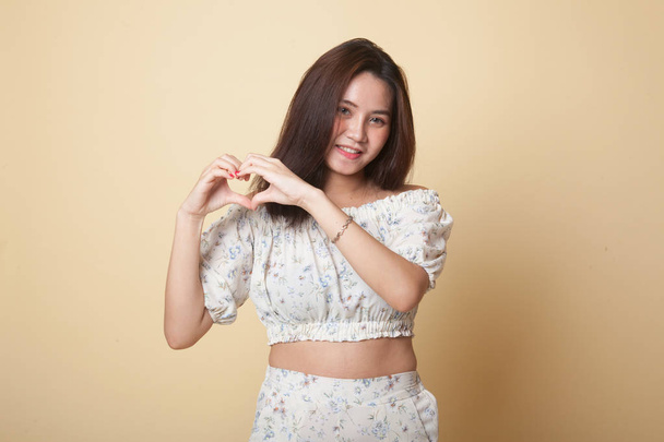 Young Asian woman show heart hand sign on beige background - Φωτογραφία, εικόνα