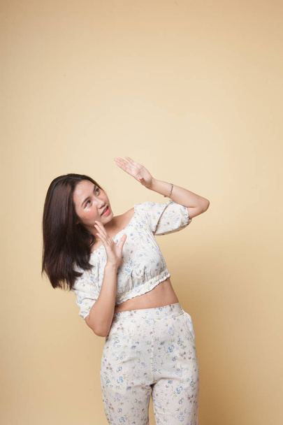 Excited young Asian woman look up on beige background - Photo, Image