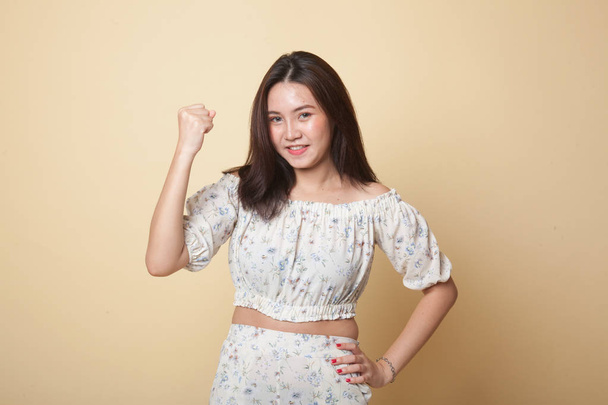 Successful  young Asian woman hold fist up on beige background - Фото, зображення