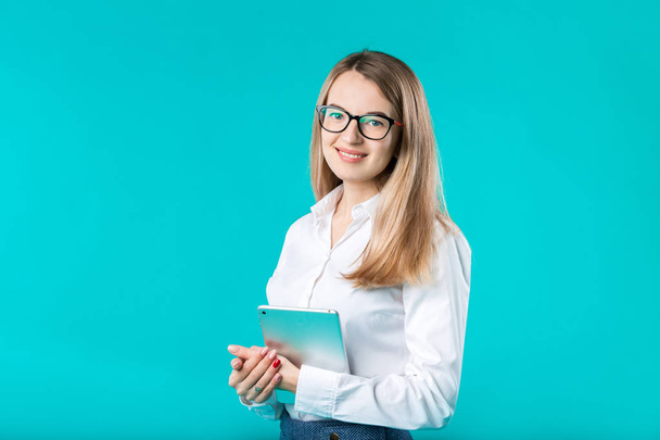Portrait young caucasian woman worker teacher trainer mentoring in white shirt office style long hair with a tablet in hand uses technology isolated bright color blue background. - Foto, immagini
