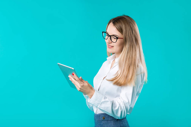 Portrait young caucasian woman worker teacher trainer mentoring in white shirt office style long hair with a tablet in hand uses technology isolated bright color blue background. - Fotografie, Obrázek