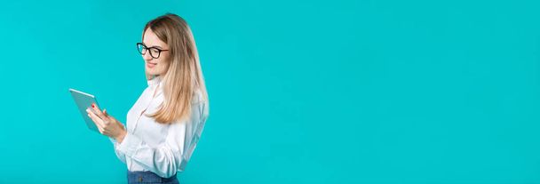 Портрет молодой кавказской женщины-работницы учитель наставничества в белой рубашке офисный стиль длинные волосы с планшетом в руке использует технологии изолированных ярко-голубой фон
. - Фото, изображение